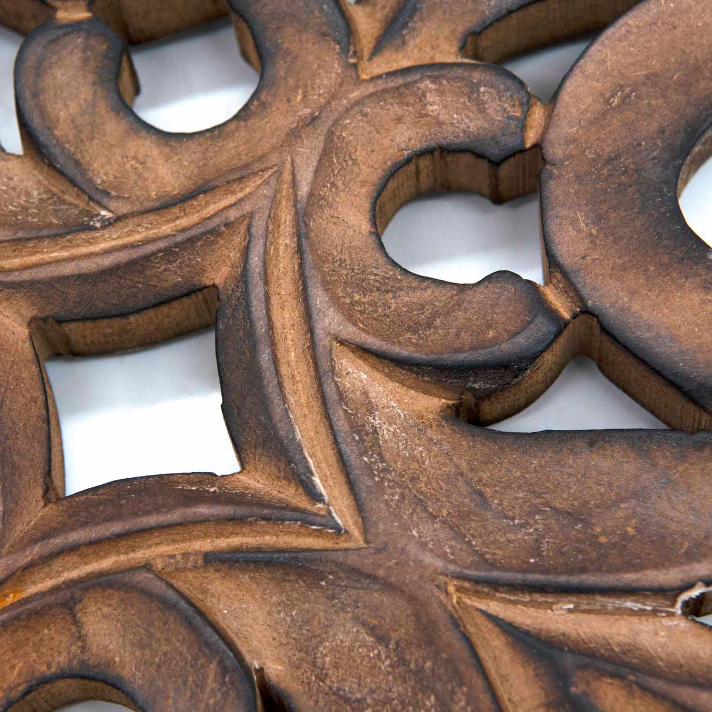 Close-up detail of mango wood cross carving showing scrolling stems and pierced leaf motifs