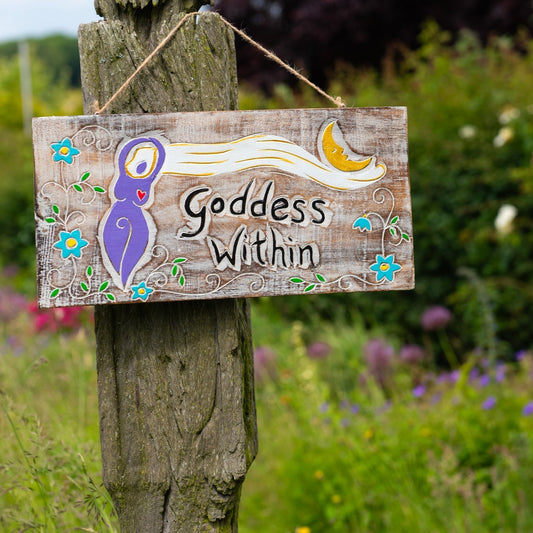Goddess Within carved wood plaque mounted on a garden post, full front view with whitewashed grain and painted detail visible