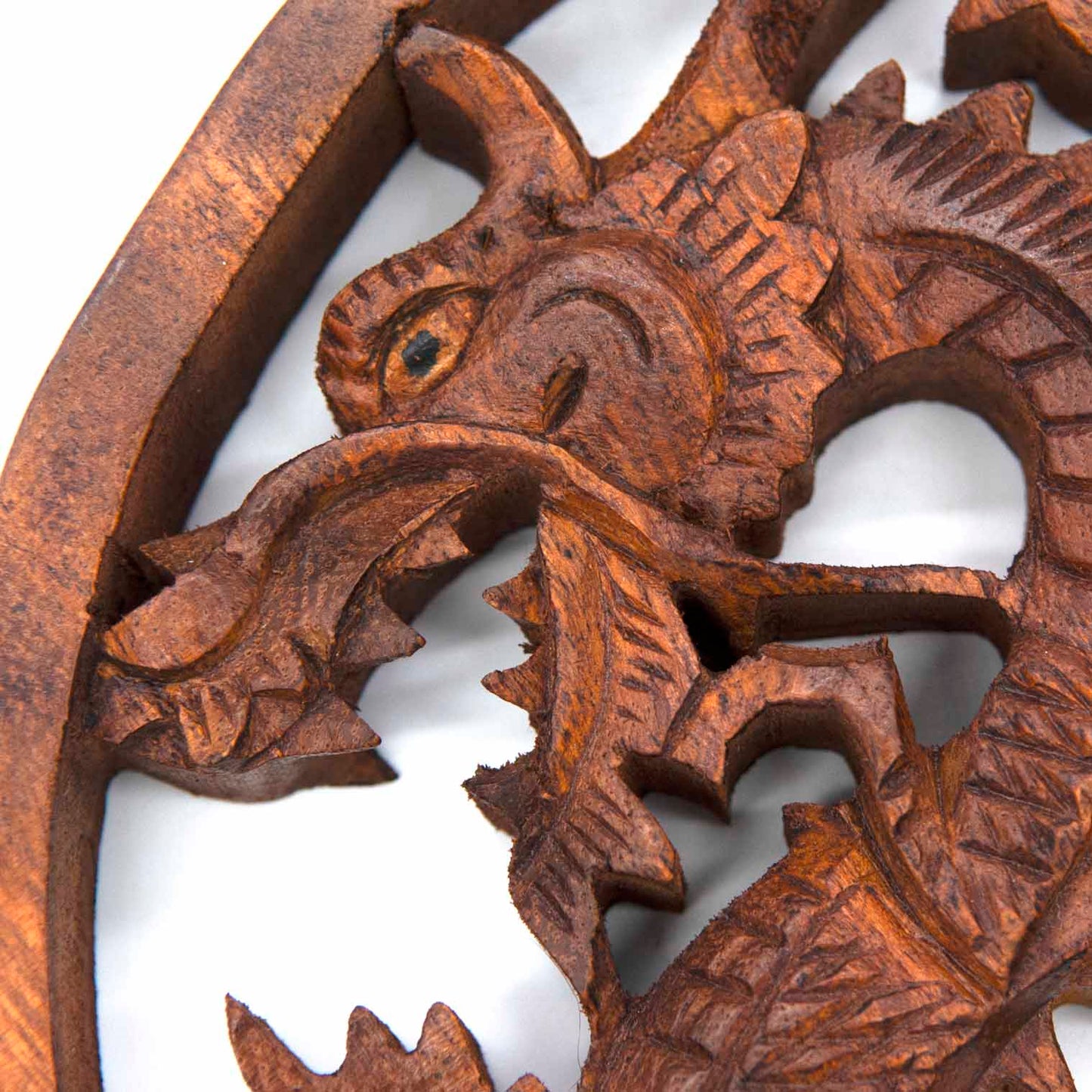 Close-up of dragon head on Indonesian carved wood plaque showing scaled texture, eye detail and open jaw