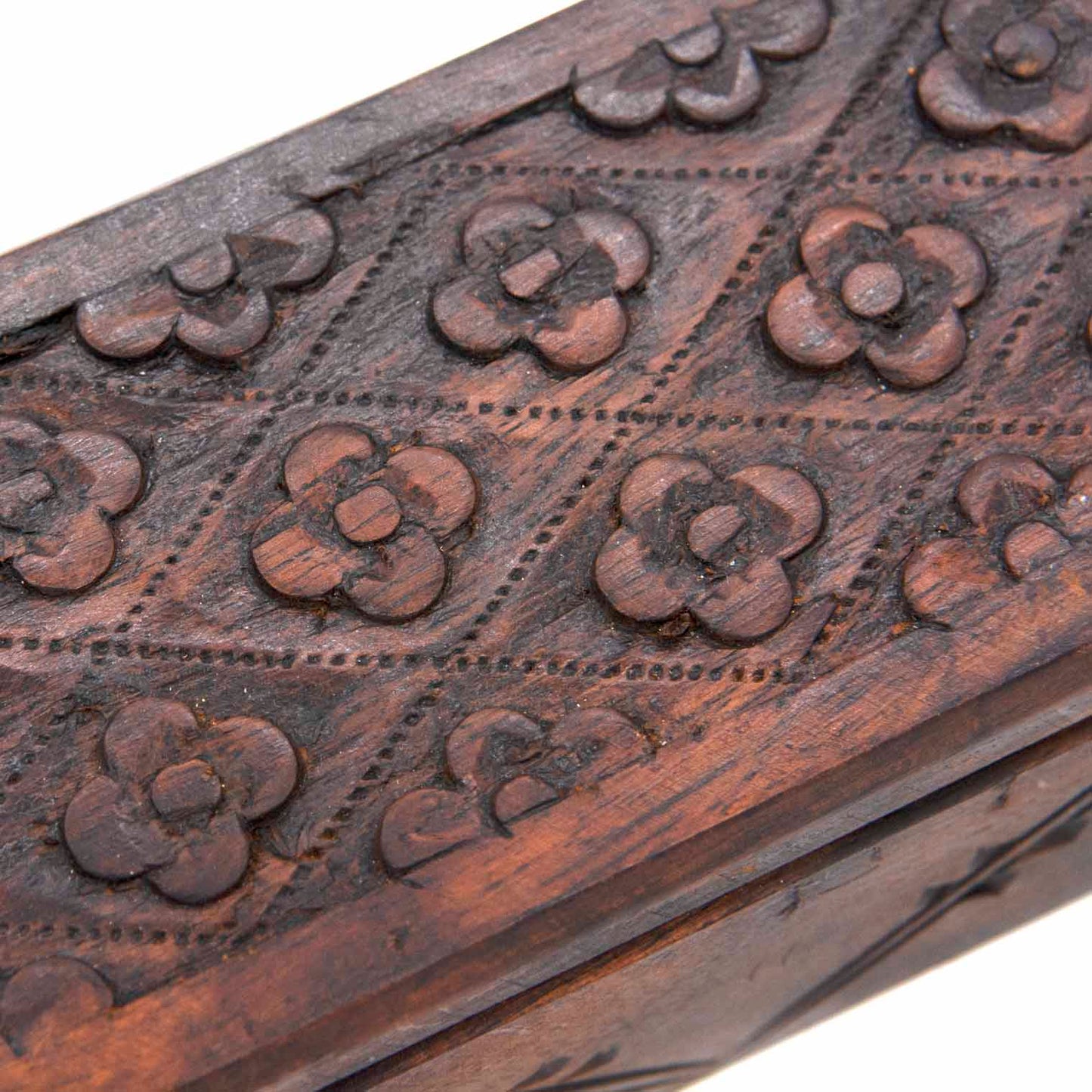 Close-up of raised flower motifs on the lid of the Indonesian carved wood long box, showing chisel detail