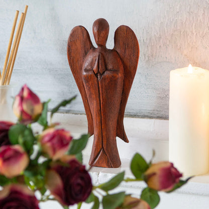 Large abstract Raintree wood angel carving on white surface with roses and candle, front view
