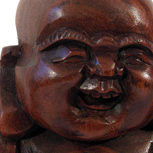 Close-up of carved wood Laughing Buddha face, smooth finish and open-mouthed expression, Indonesia