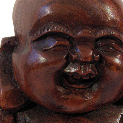 Close-up of carved wood Laughing Buddha face, smooth finish and open-mouthed expression, Indonesia
