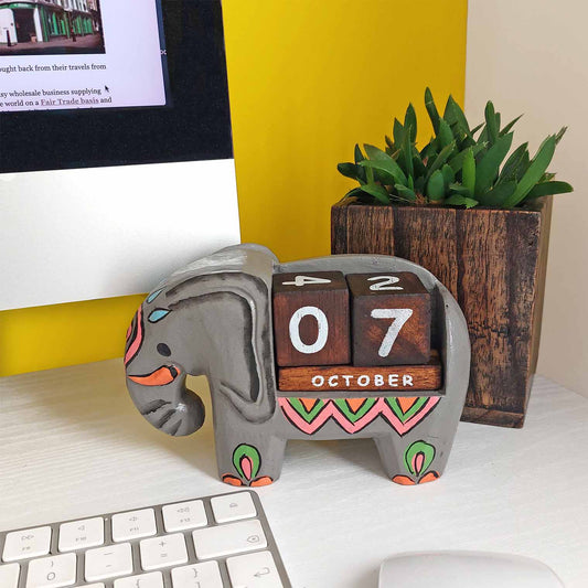 Hand-painted grey wooden elephant perpetual calendar on a desk, showing October date, Indonesia
