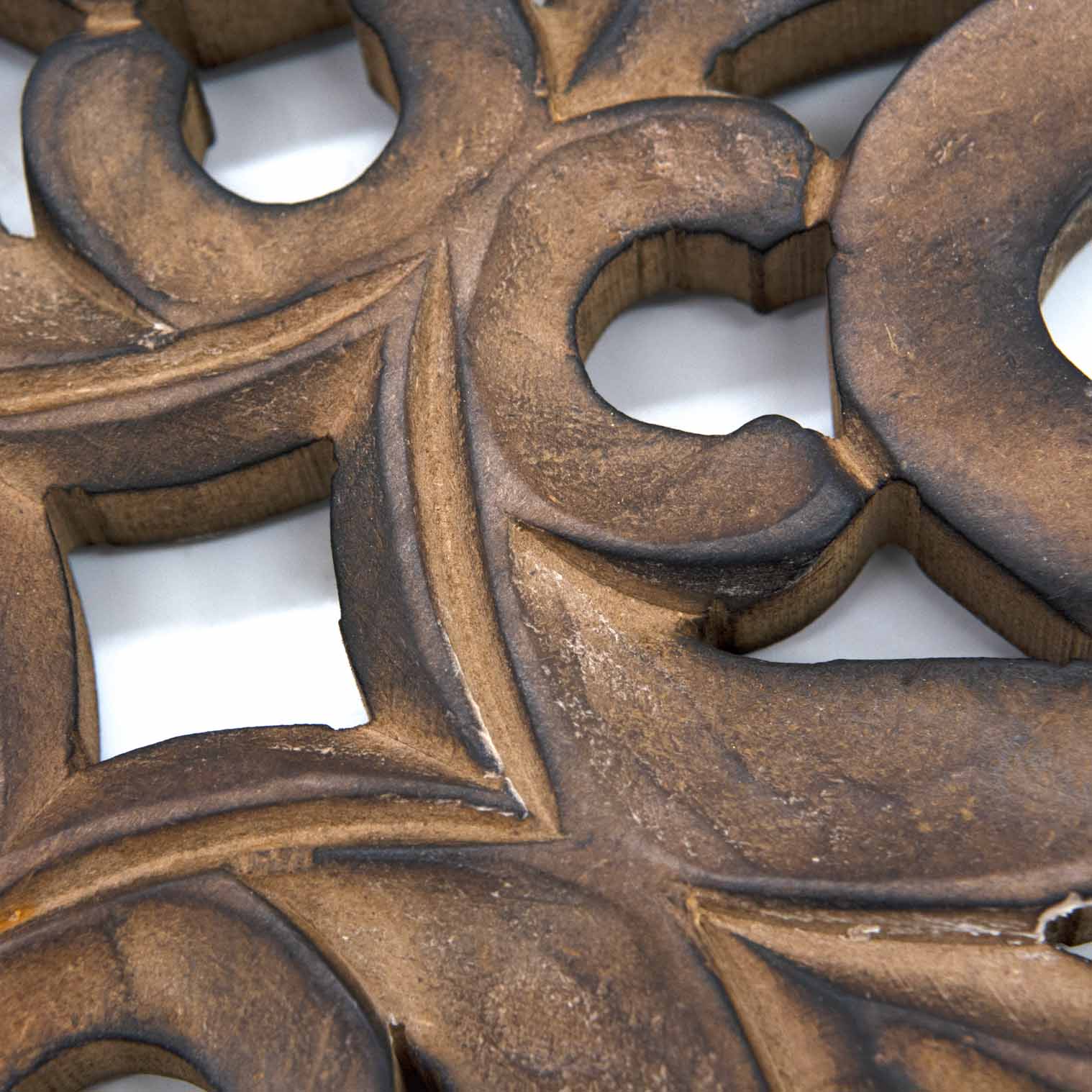 Close-up detail of mango wood cross carving showing scrolling stems and pierced leaf motifs