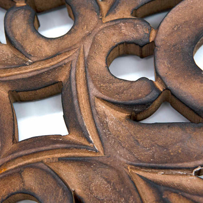 Close-up detail of mango wood cross carving showing scrolling stems and pierced leaf motifs