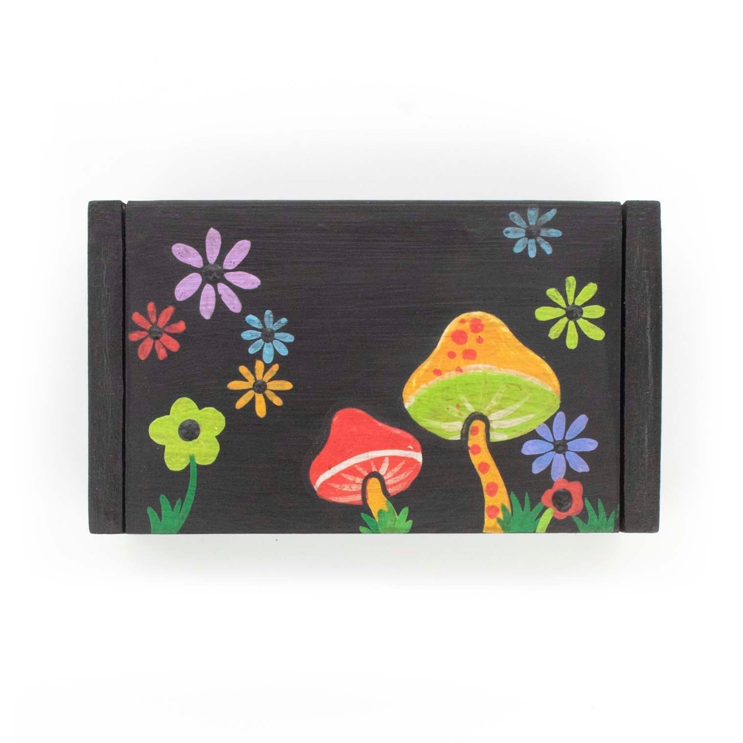 Top-down view of black wooden box lid showing toadstool and daisy painting, Indonesia