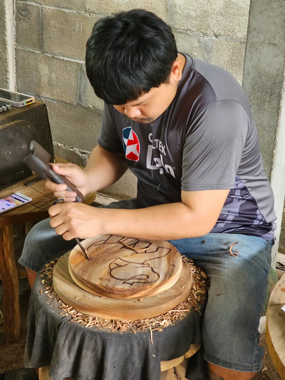 Person working on a wooden project with tools in a workshop setting.