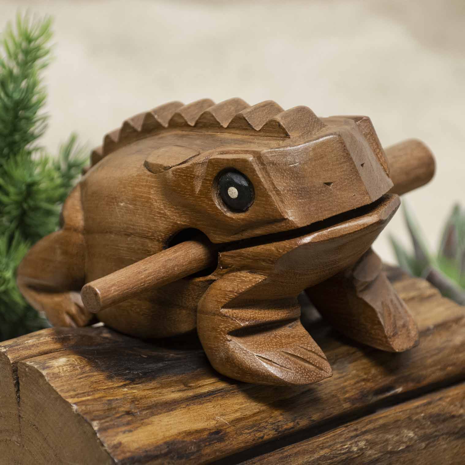 Medium acacia wood frog guiro with striker, front three-quarter view on wooden surface, northern Thailand