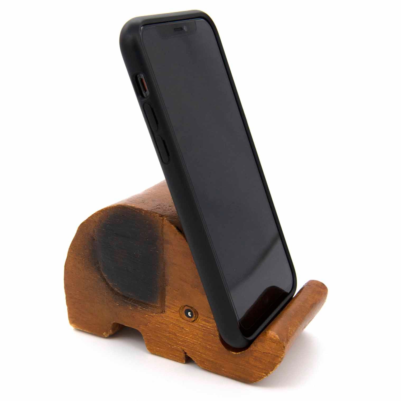 Carved wooden elephant phone stand with phone, front three-quarter view showing body and ear, white background