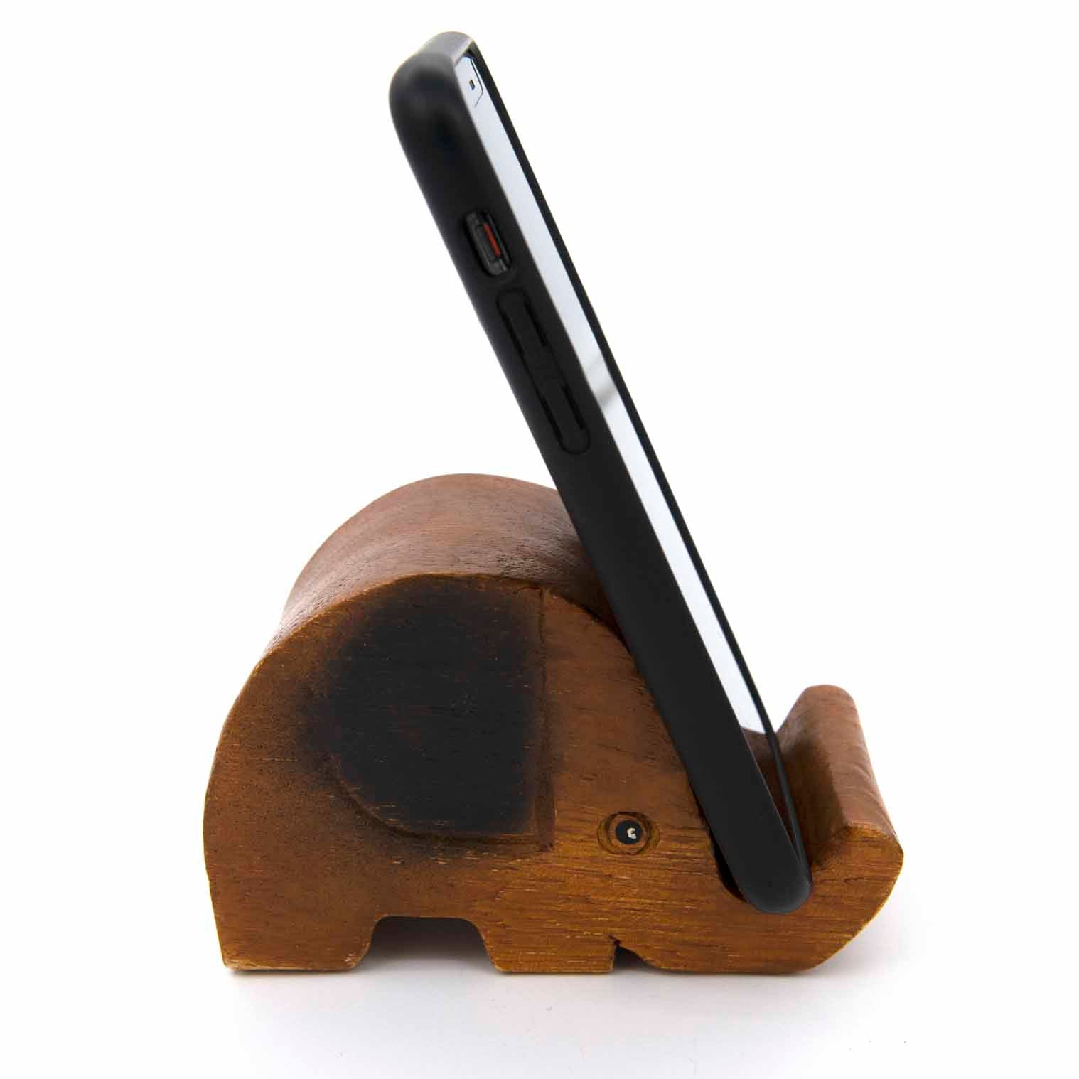 Carved elephant phone stand holding a smartphone upright, side view showing trunk slot, white background