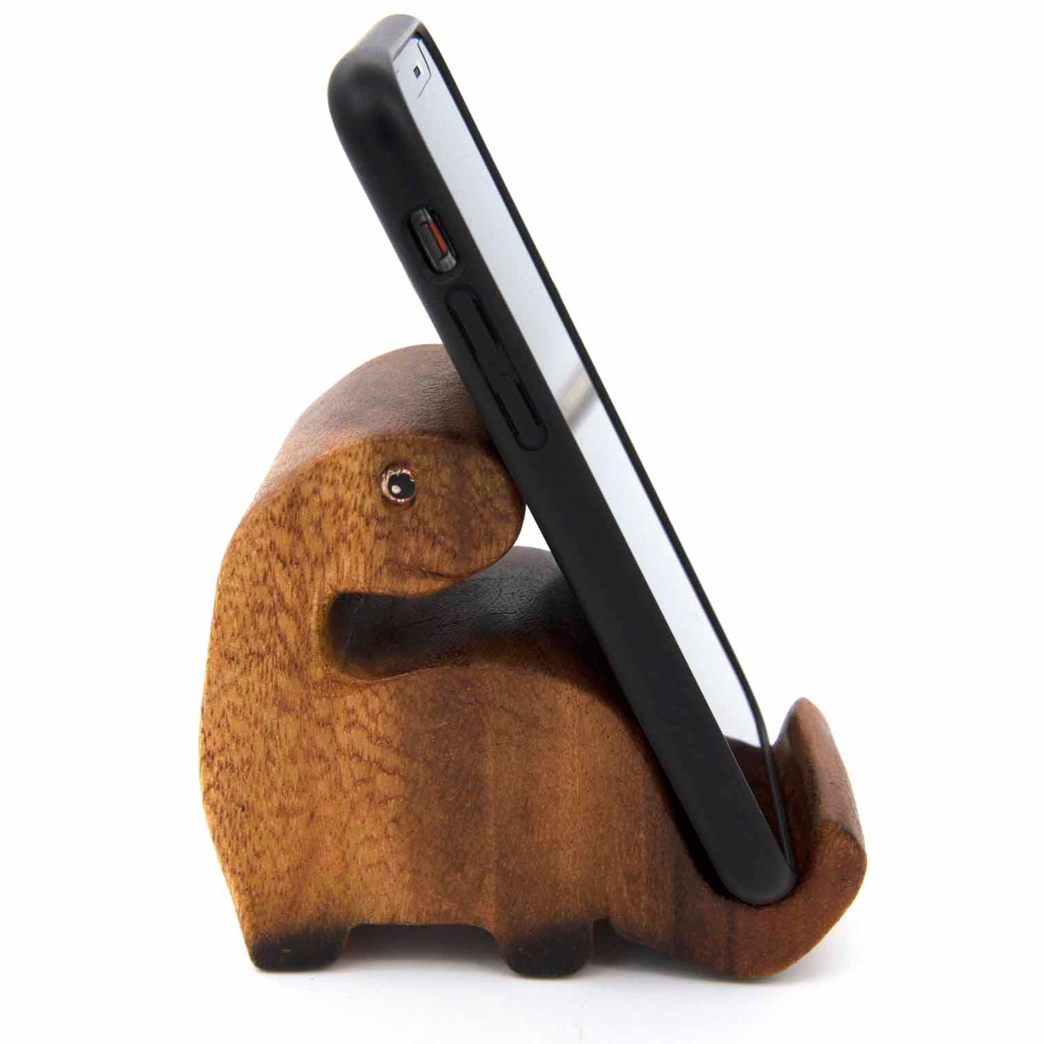 Carved dinosaur phone stand holding a smartphone, side view showing neck and tail cradle, white background