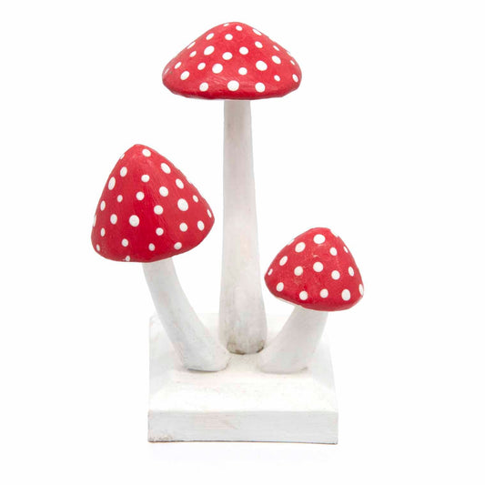 Three carved red and white wooden toadstools on a shared white base, front view on white background