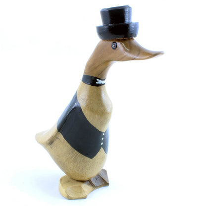 Carved bamboo root groom duck in black tailcoat with painted bow tie and top hat, side view on white background