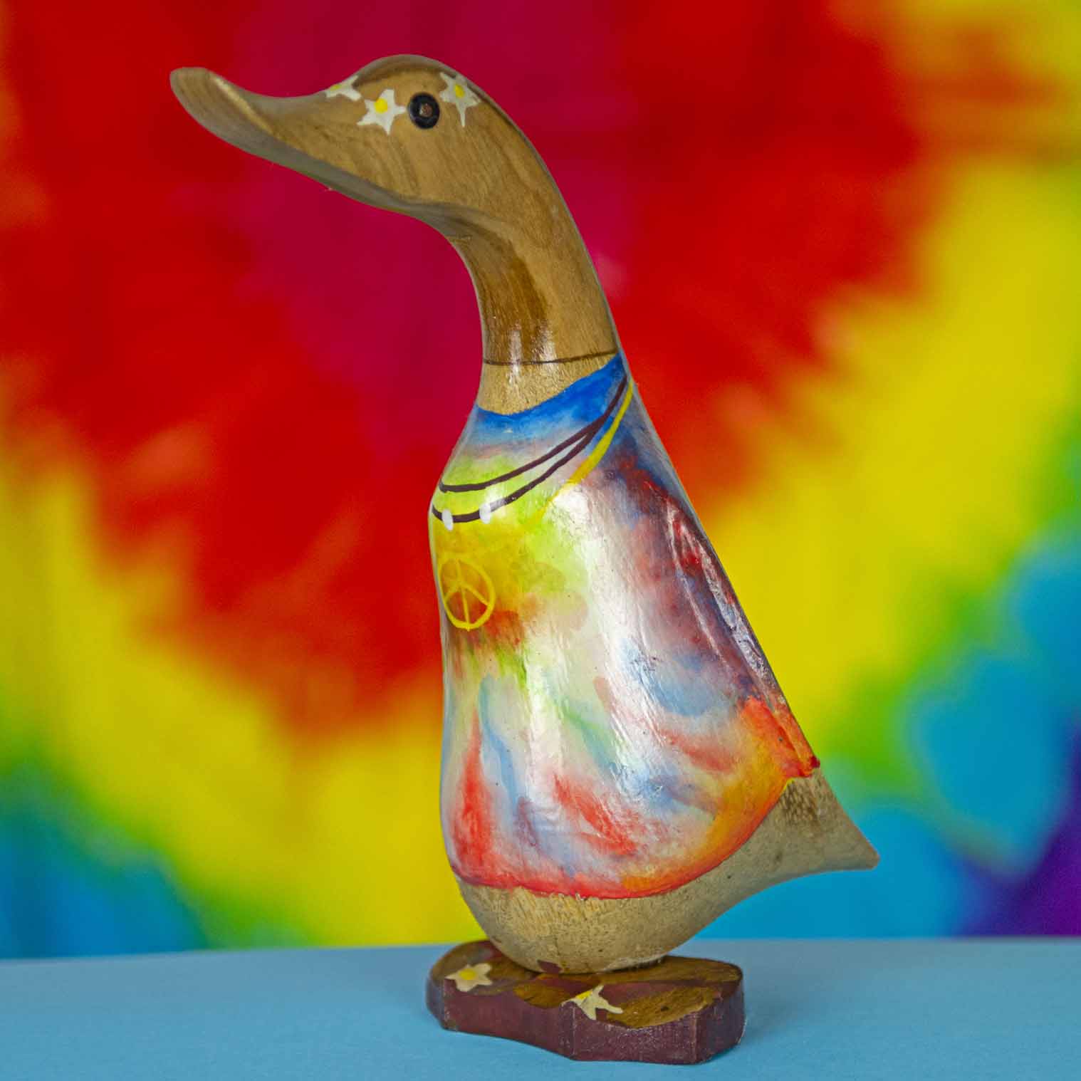 Tie-dye painted bamboo root duck from Bali, front three-quarter view against rainbow background