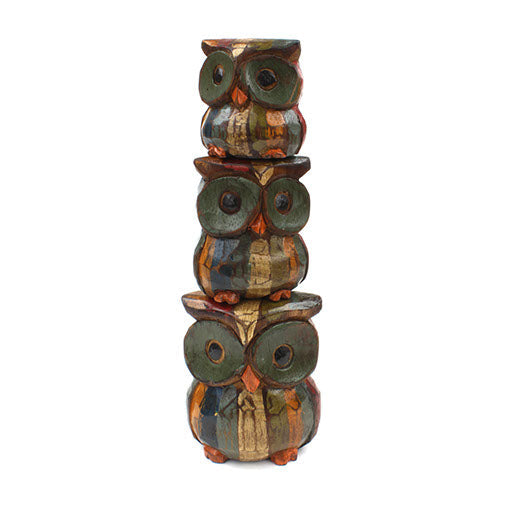 Three Albizia wood owls stacked in a tower showing multicolour patchwork paint and disc eyes