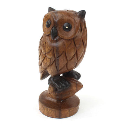 Carved wooden owl perched on branch stub, side-angled front view showing wing and feather scale texture