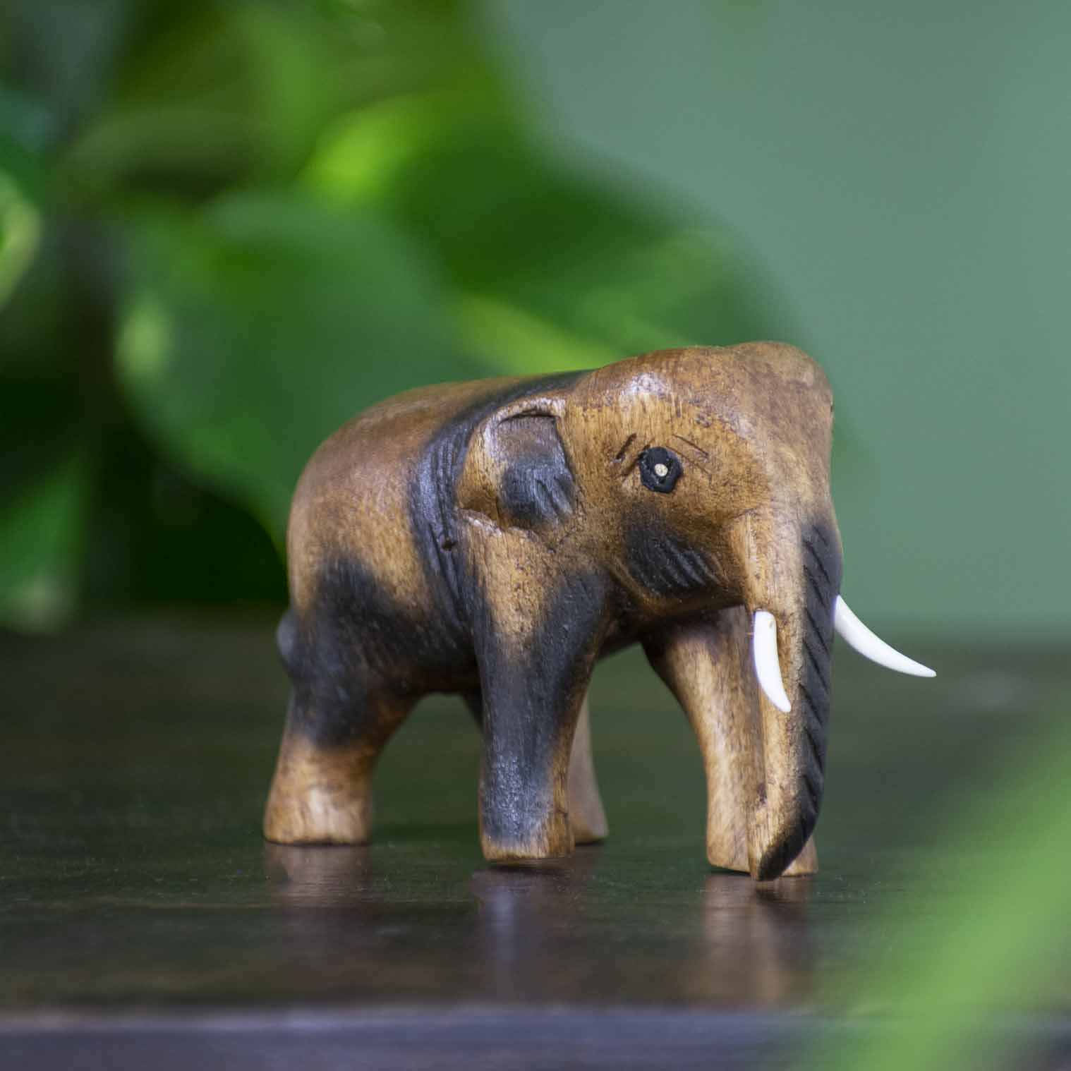 Small hand-carved Raintree elephant figurine with dark-stained detail, side view, northern Thailand