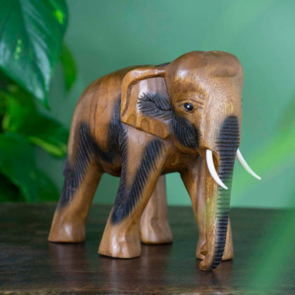 Large hand-carved Raintree elephant figurine with ribbed trunk detail, side view on dark surface, Thailand