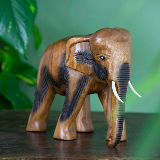 Large hand-carved Raintree elephant figurine with ribbed trunk detail, side view on dark surface, Thailand