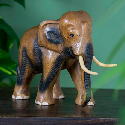 Extra large hand-carved Raintree elephant with painted toenails and ribbed trunk, side view on dark surface