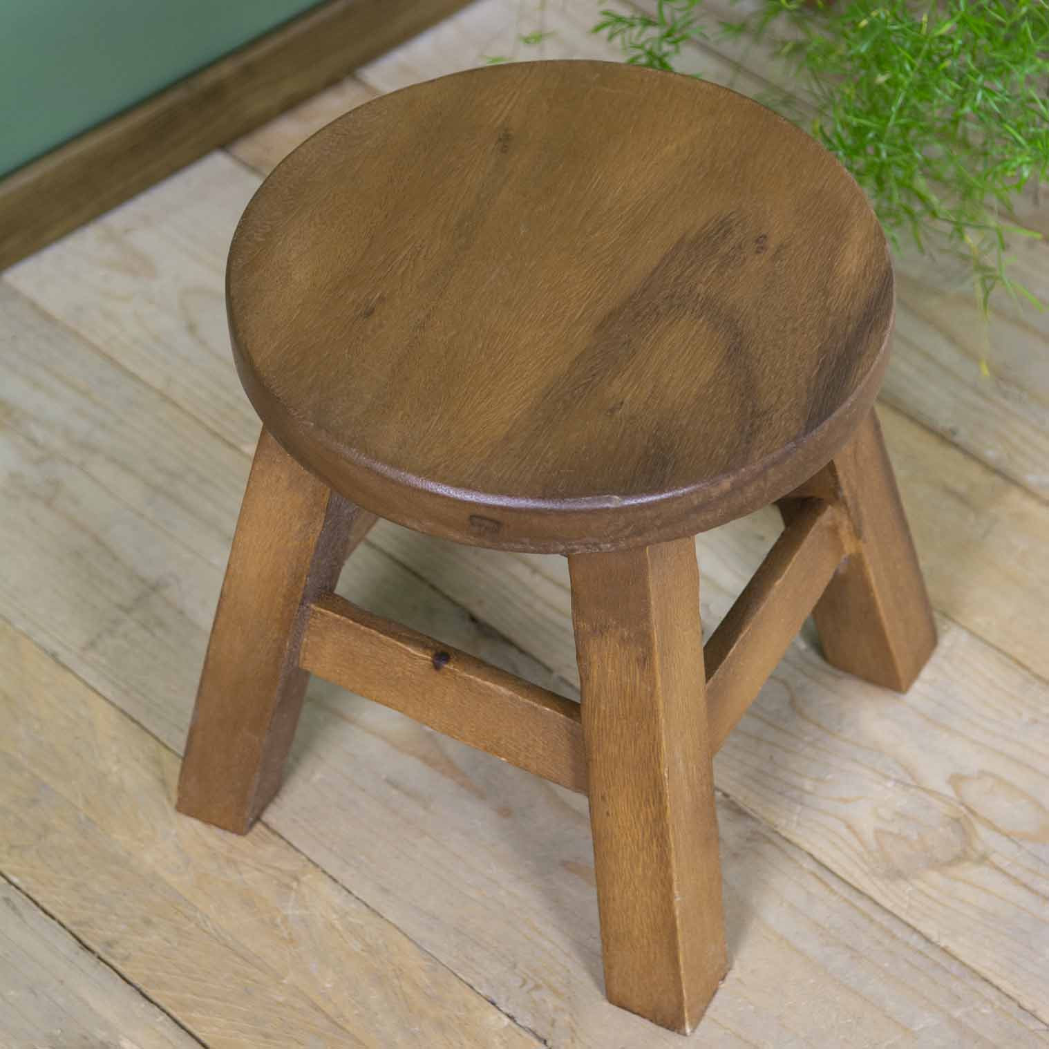 Plain Raintree wood stool with round seat and four splayed legs, warm grain visible, northern Thailand