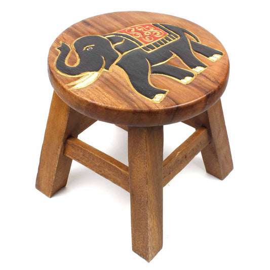 Hand-carved elephant stool in Raintree wood on white background, showing full side profile with gold-outlined legs and red cl