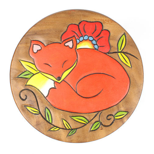 Top-down view of Raintree wood stool seat with carved sleeping fox in orange, surrounded by painted green leaves and red popp