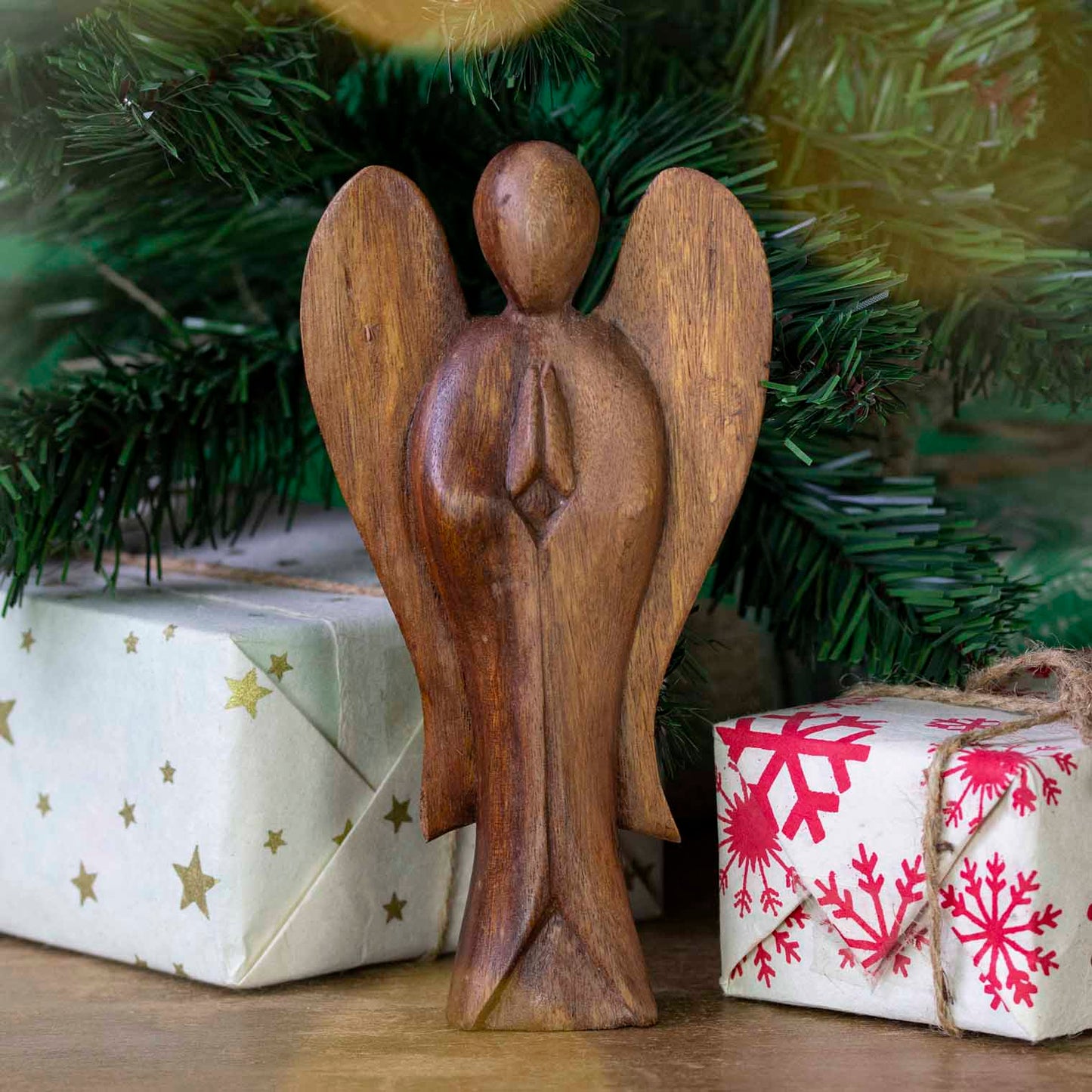 Large hand-carved Balinese abstract angel figurine displayed beneath a Christmas tree