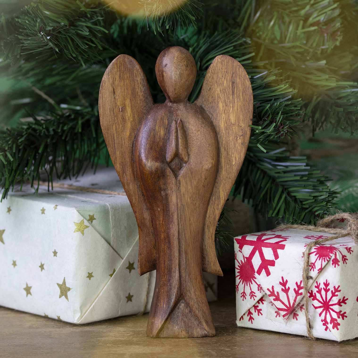 Large hand-carved Balinese abstract angel figurine displayed beneath a Christmas tree
