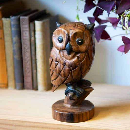 Carved acacia wood owl on branch with turned round base, front three-quarter view on bookshelf, northern Thailand