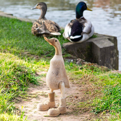 Natural unvarnished bamboo root duck with carved boots, photographed outdoors near a pond with real ducks