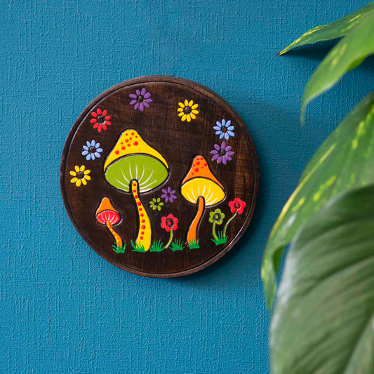 Hand-painted mushroom wood plaque hung on a blue wall, yellow and green toadstool caps on dark stained ground