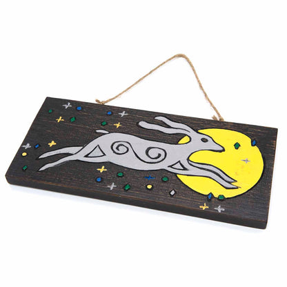 Angled side view of moon hare painted wood plank showing thickness and twine hanger, star details visible on dark ground