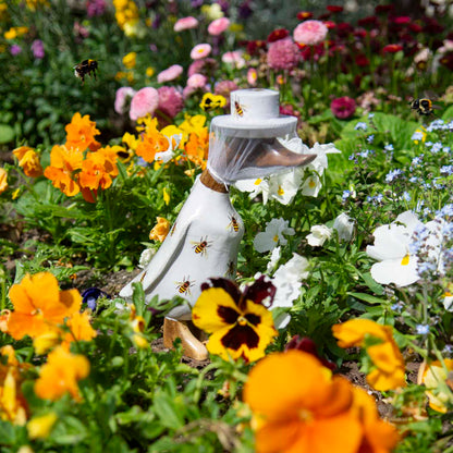 Beekeeper bamboo root duck with net veil and bee-printed body, photographed among garden flowers with real bumblebees