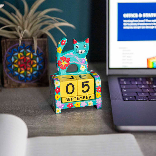 Teal hand-painted wooden cat perpetual calendar on a desk showing September date, Indonesia
