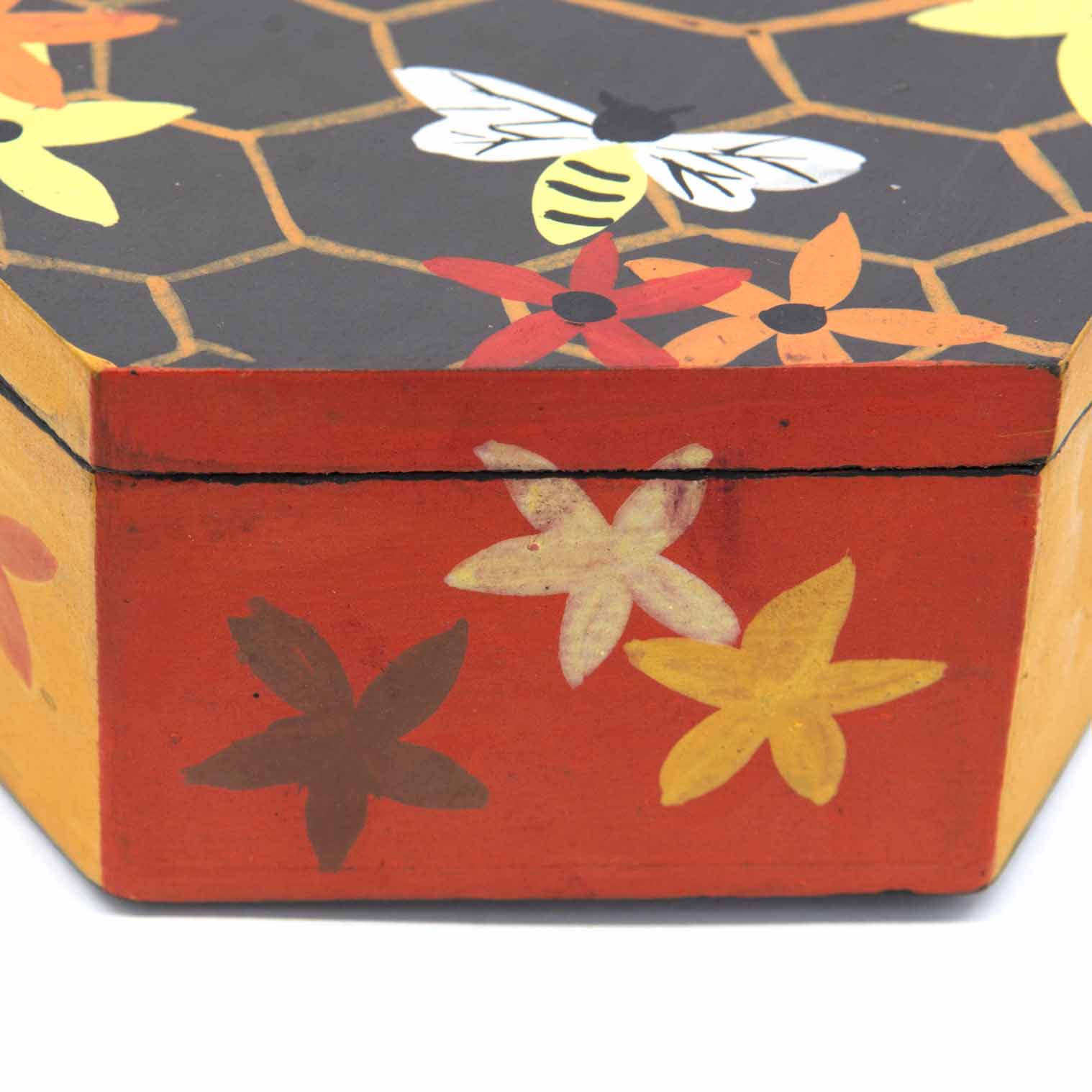 Side view of hexagonal bee box showing red and amber painted base with flower motifs, Indonesia