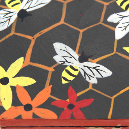 Close-up of hand-painted bee and honeycomb detail on wooden box lid, Indonesia
