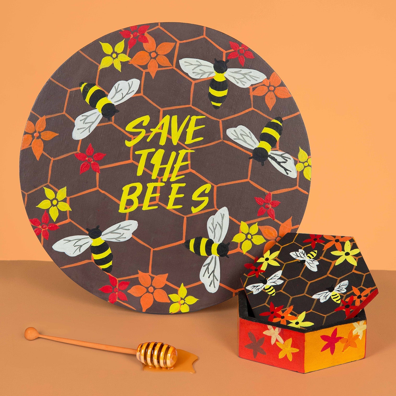Hand-painted hexagonal bee box shown alongside a round painted bee board and honey dipper, Indonesia