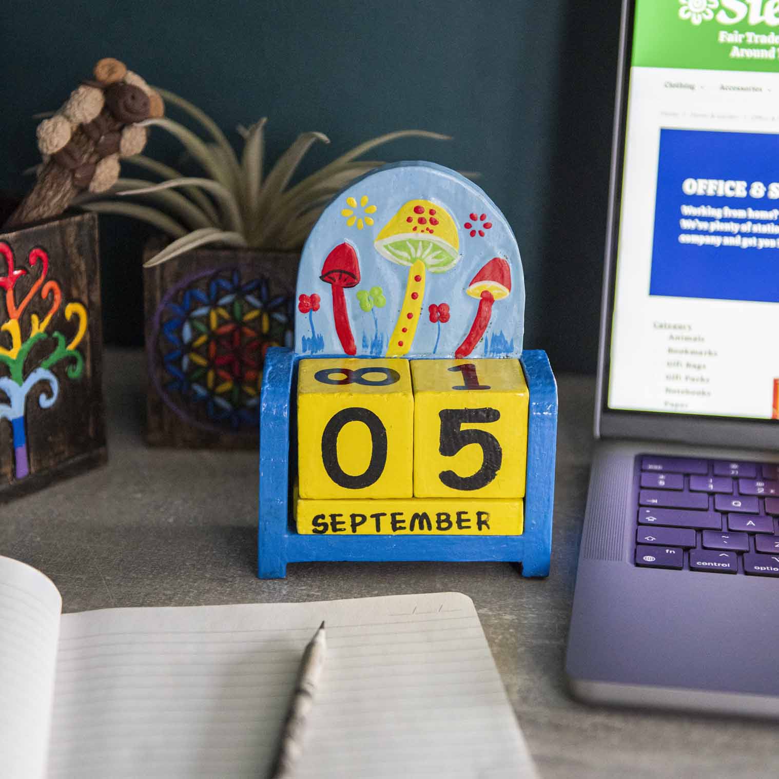 Painted wooden mushroom perpetual calendar on a desk showing September date, blue and green toadstool scene