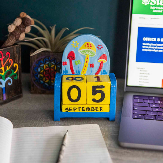 Painted wooden mushroom perpetual calendar on a desk showing September date, blue and green toadstool scene