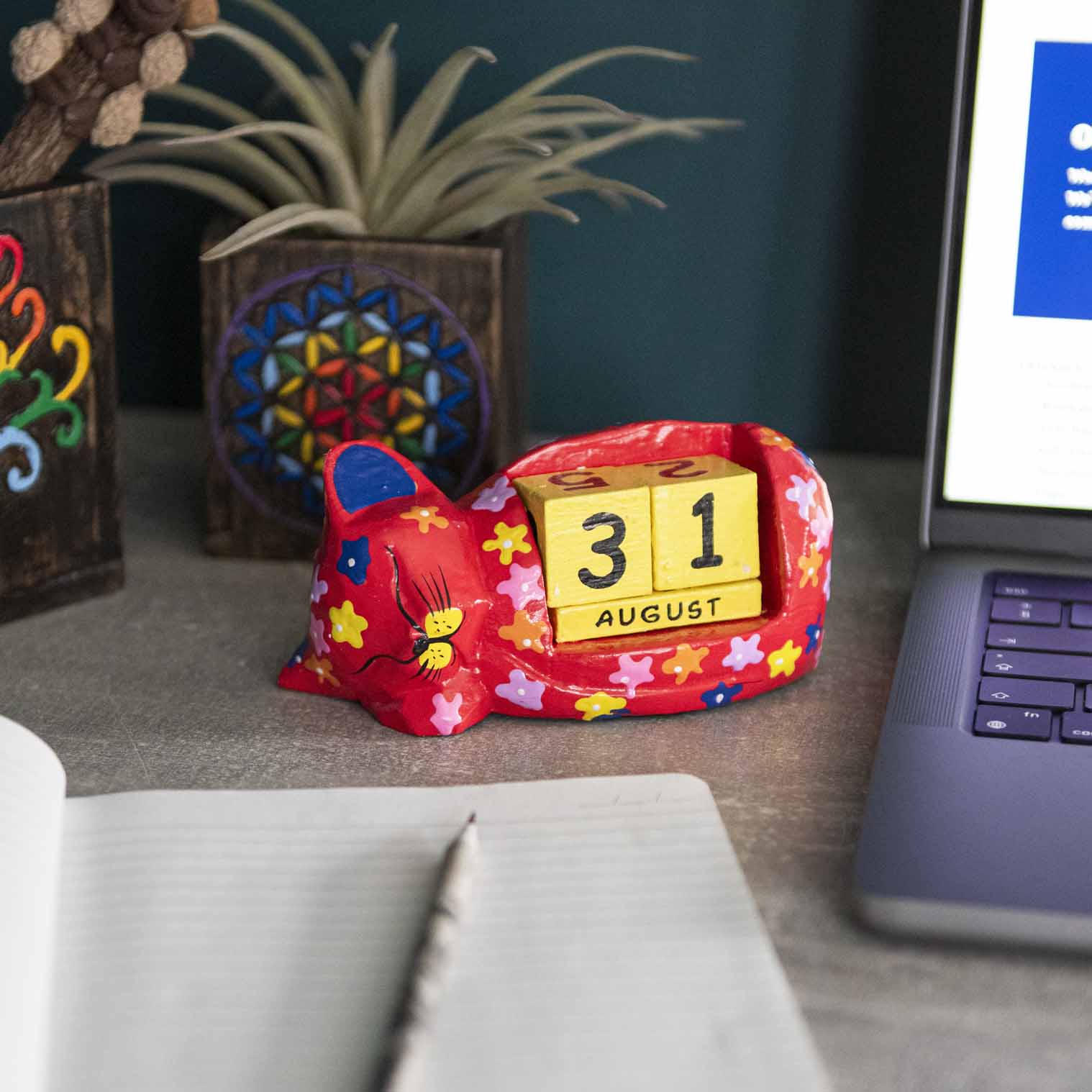 Red painted wooden sleeping cat perpetual calendar on a desk showing August date, Indonesia