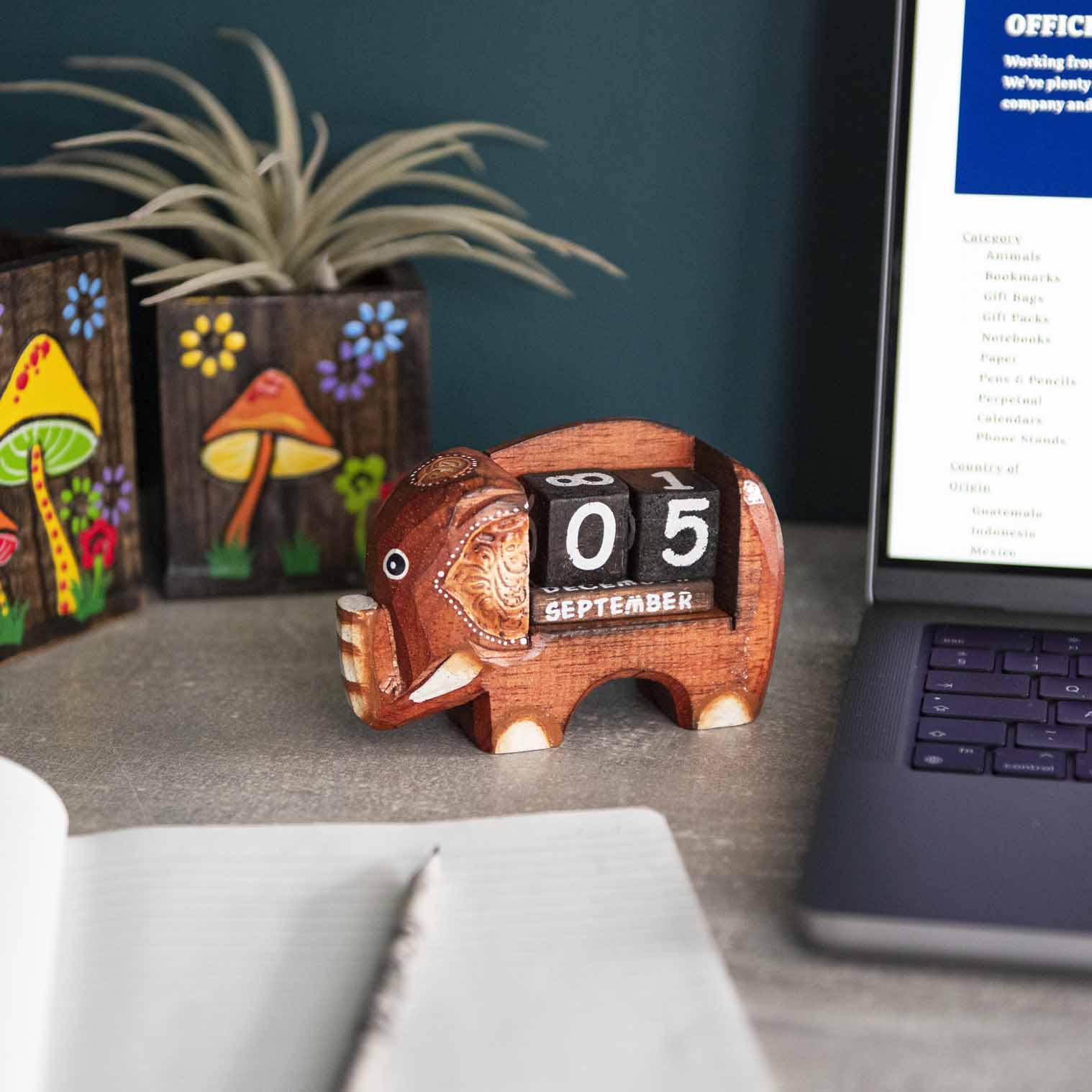 Small carved dark wood elephant perpetual calendar on a desk showing September date, Indonesia