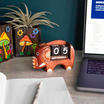 Small carved dark wood elephant perpetual calendar on a desk showing September date, Indonesia