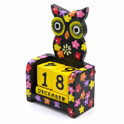 Three-quarter view of black floral owl calendar with yellow rotating date blocks, Indonesia