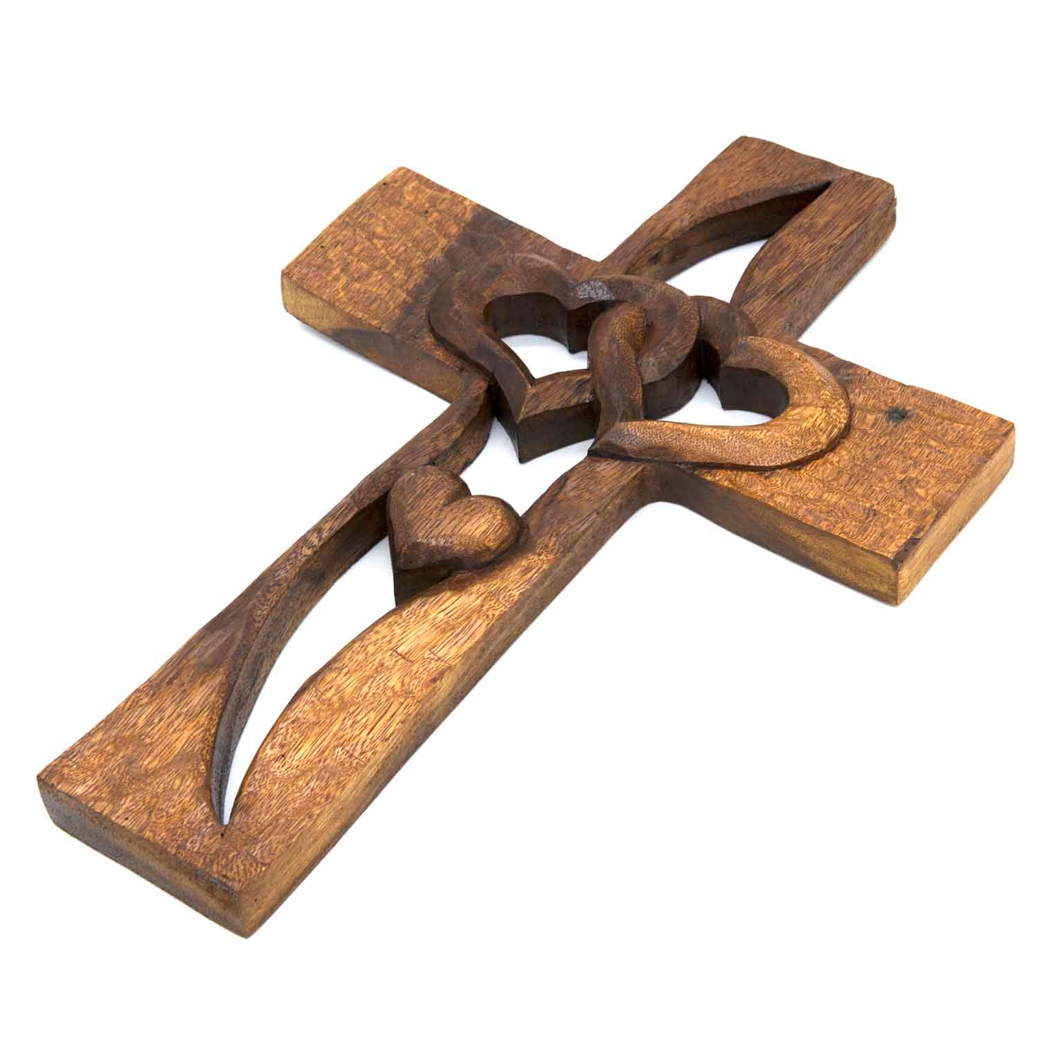 Carved wood cross with interlocking hearts, angled view showing chisel-textured surface and depth of carving