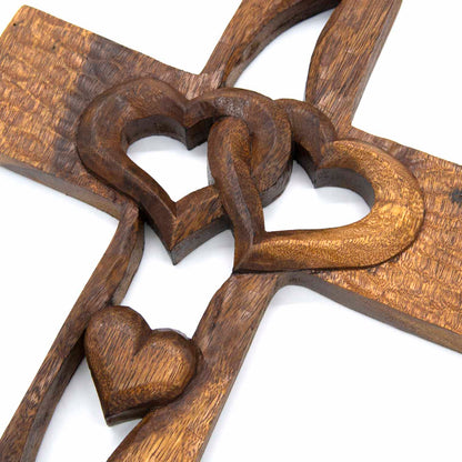 Close-up of interlocking hearts at centre of carved wood cross, showing grain and chisel marks, Indonesia