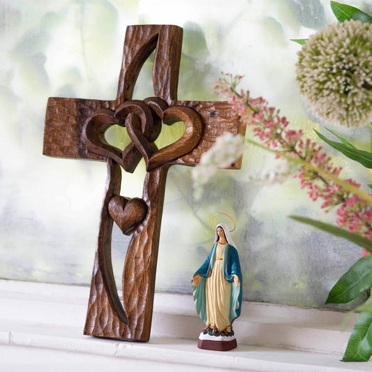 Carved wood cross with interlocking hearts, leaning against wall in lifestyle setting, Indonesia