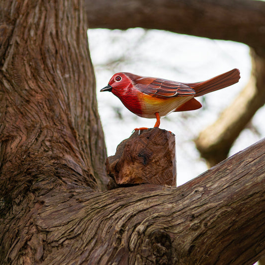 Hand-painted wooden robin perched on a natural wood stand in a tree, Bali Indonesia