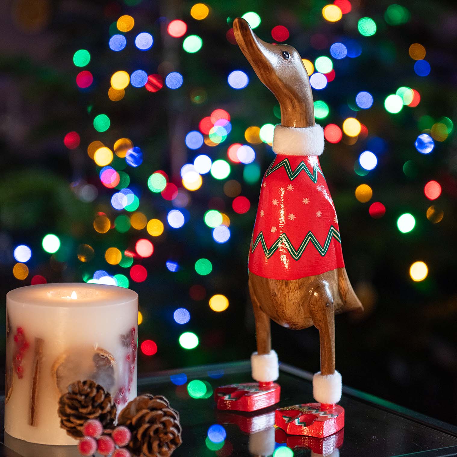 Bamboo duck in red Christmas jumper with green zigzag trim, photographed against bokeh Christmas lights